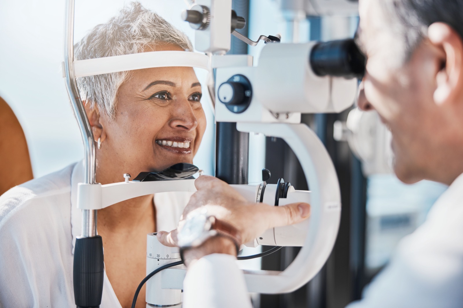 Smiling patient having her eyes examined at a slit lamp at Arbor Eyecare